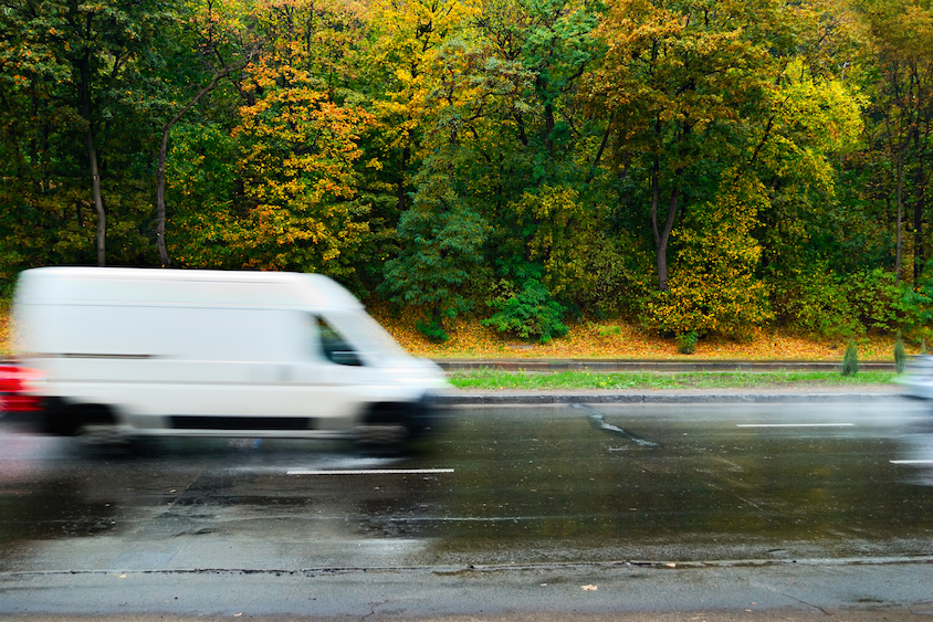 White van driving on wet road in autumn