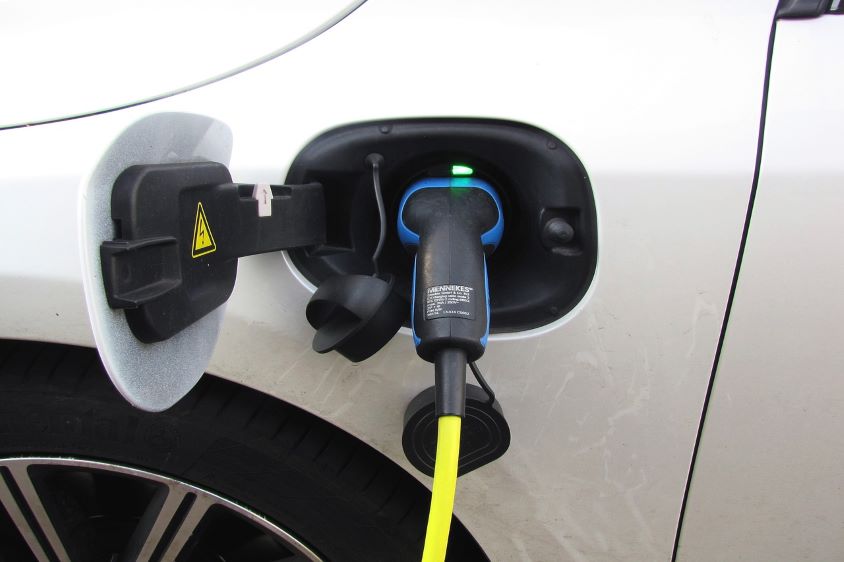 White electric car with charging plug inserted