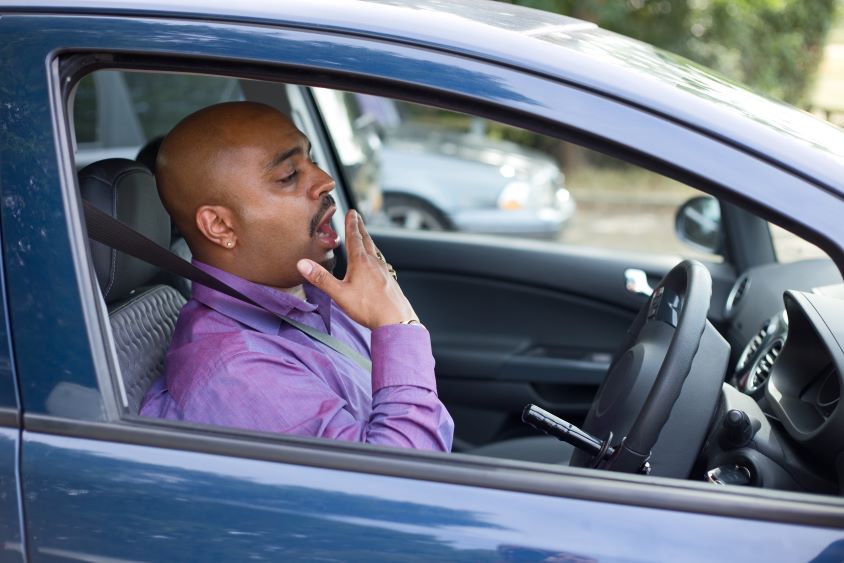 Male driver sat in car yawning