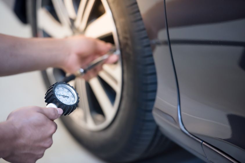 Pair of hands holding a pressure gauge, measuring car tyre pressure