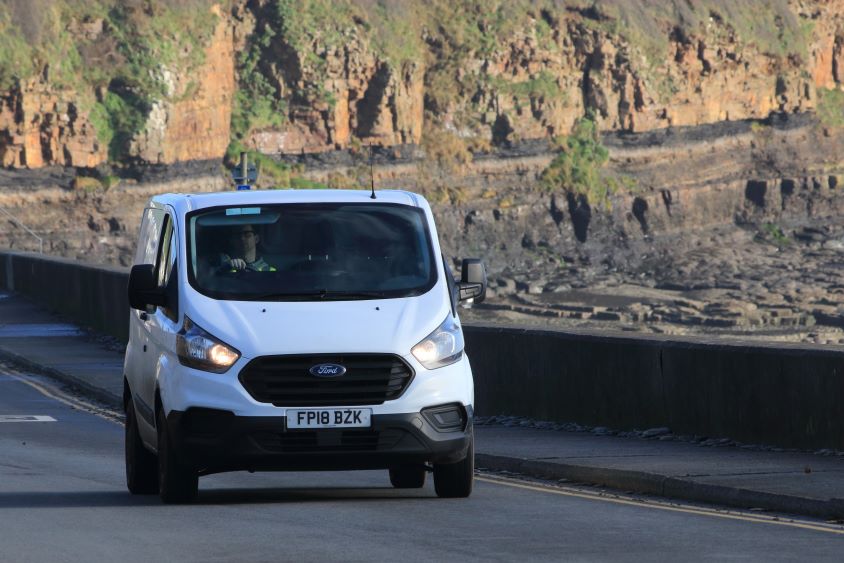 White Ford van driving on road