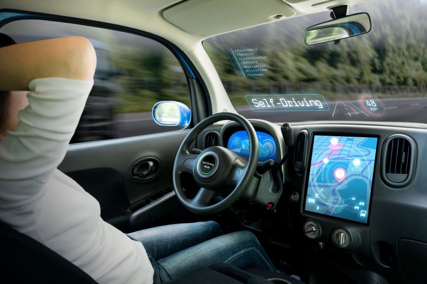 Interior of a self driving car, male driver with his hands behind his head