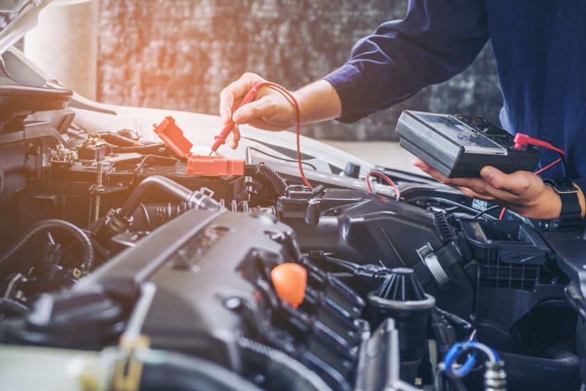 Mechanic using orange equipment to service a car battery