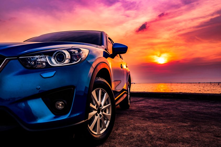 Car parked on beach with sunset in background