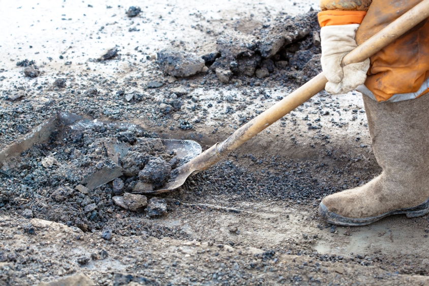 Worker in hi-vis apparel using a spade during road maintenance
