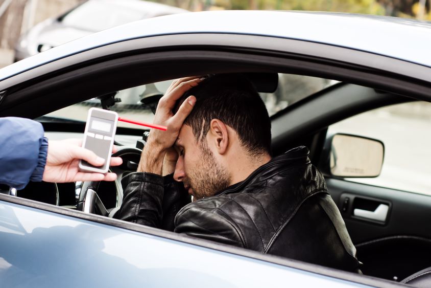 Distressed man in car being encouraged to take a breathalyzer test