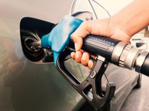 A hand holding a petrol pump refuelling a car