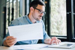 Man at a laptop simultaneously looking at documents