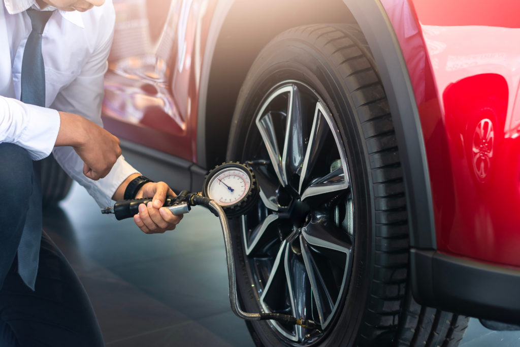 Image of a man kneeling to check the pressure of his vehicle's tyres