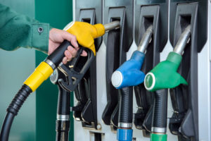 Close-up photo of a man lifting a fuel nozzle from a pump.