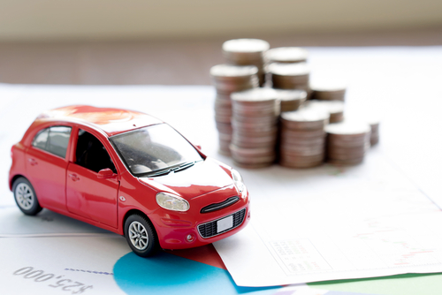 Image of a toy car alongside a financial statement with a stack of coins in the background