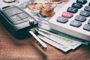 Image of a set of car keys, a calculator and loose change on a desk