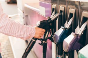 Hand lifting a fuel nozzle at petrol station