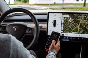 Interior of Tesla Model 3 with driver connecting via smartphone