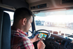 Truck driver in cab using satnav device to plan route