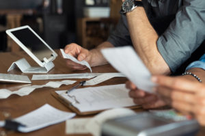 Closeup of people calculating expenses with receipts and pen and paper