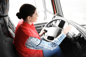 Young female driver sitting in cab of truck