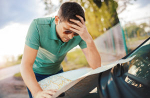 : Image of a man reading a map on the bonnet of a car