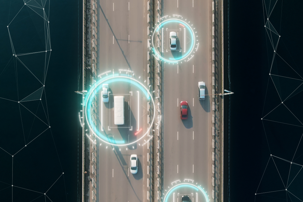 Overhead view of vehicles on a motorway with digital tracking overlay.