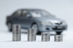 Silver coins stacked in front of grey toy car