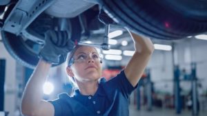 A female mechanic works underneath a vehicle