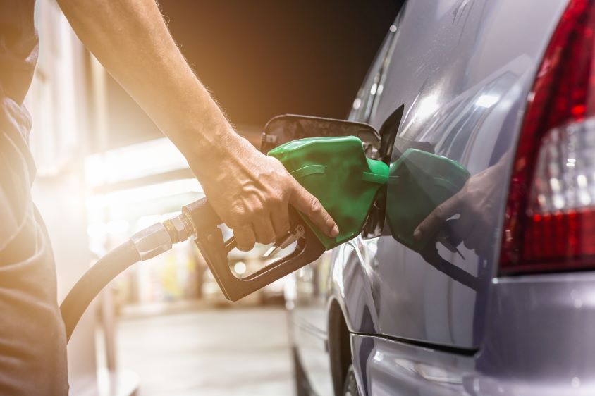 Green fuel nozzle inserted into a silver car