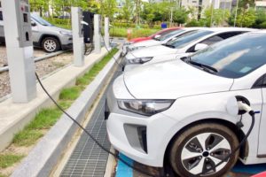 Row of white cars being charged in car park