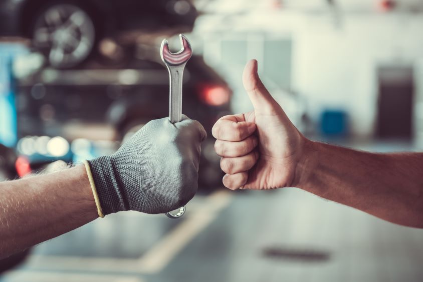 Two arms are shown. One gives a thumbs up, the other holds a spanner.