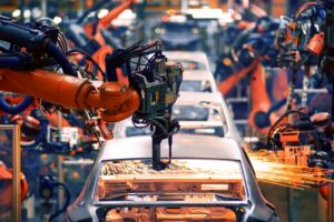 A production line with a row of cars being built, sparks flying from machinery