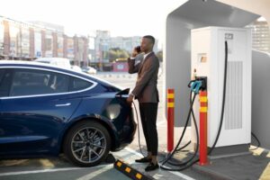 Man stood next to electric car whilst it charges