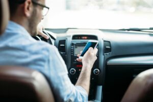 Man using phone whilst driving, ignoring the road