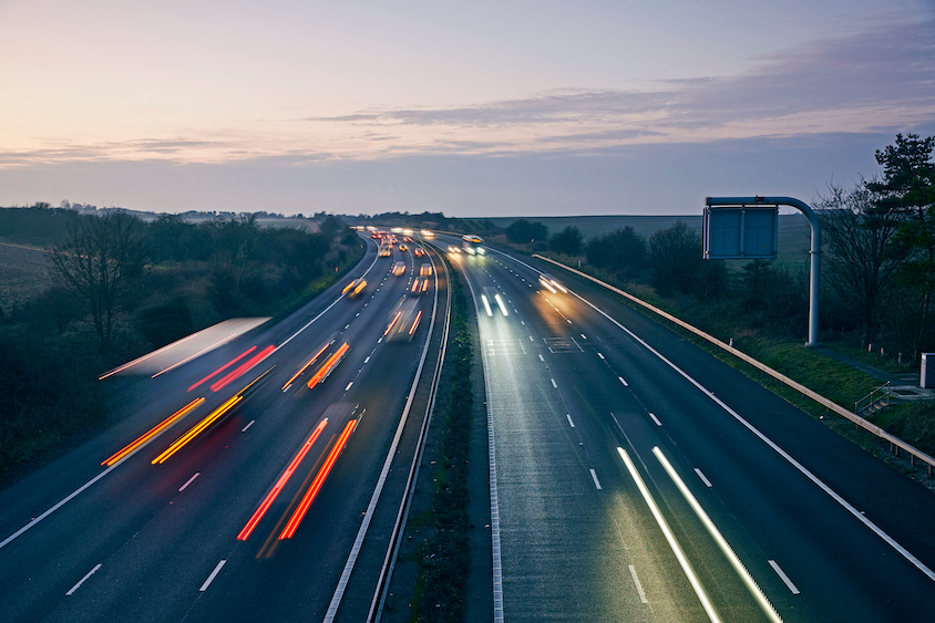 Motorway with fast moving vehicles at sunset