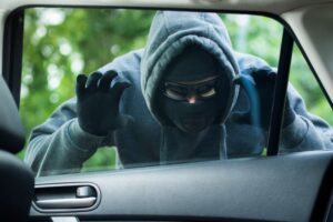 Thief in balaclava peering through car window