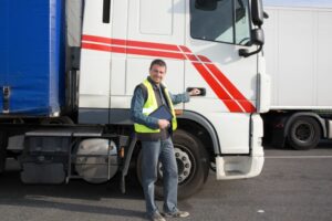 driver in front of hgv holding tablet