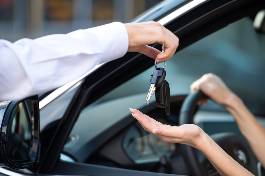 Salesman handing keys to driver in vehicle