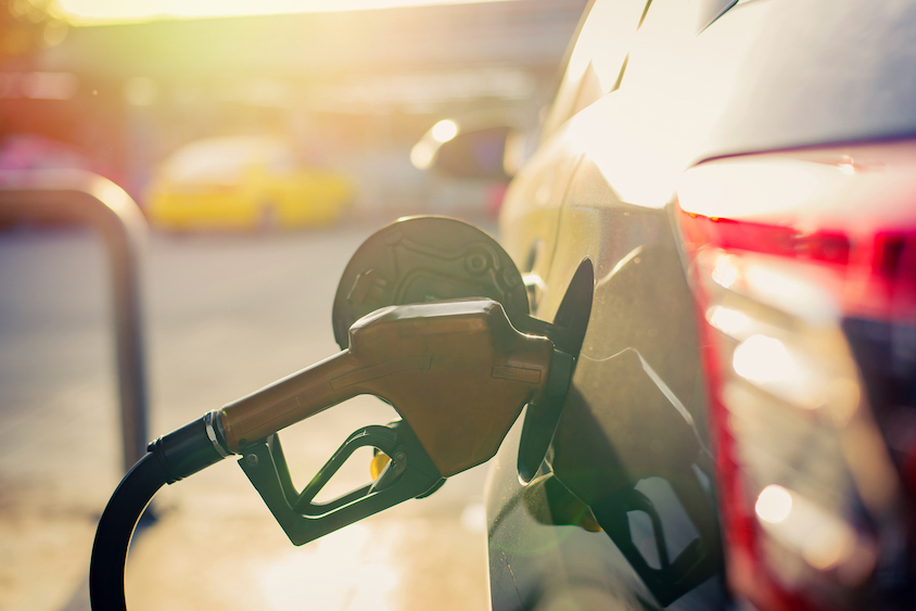 fuel nozzle inserted into car at petrol station