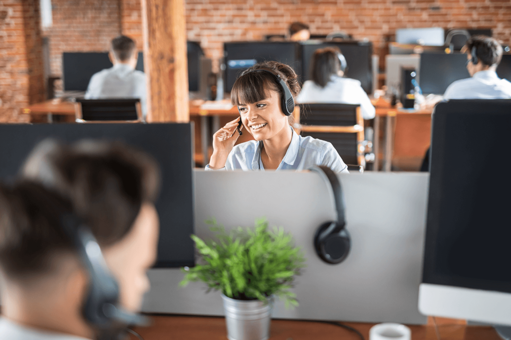 Saleswoman sat at her desk smiling whilst on a call